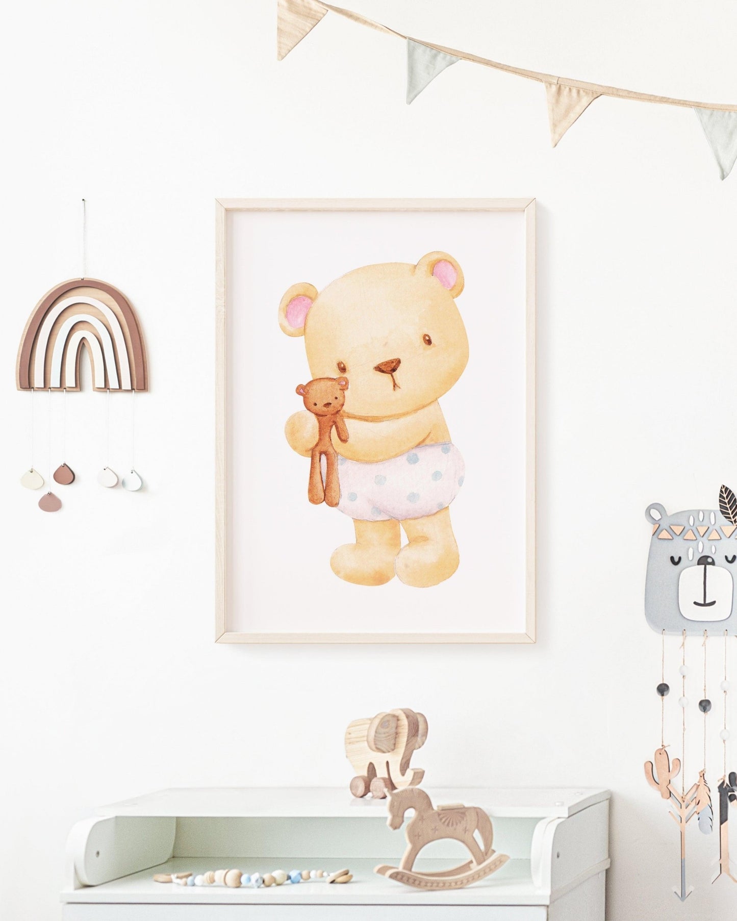 Poster con tenero orsetto che abbraccia un peluche, appeso alla parete di una cameretta decorata con arcobaleno in legno e giocattoli.