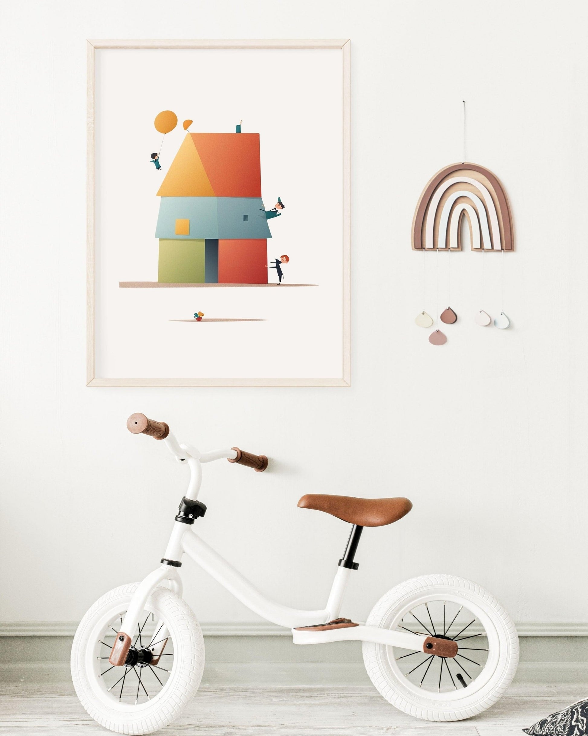 Poster “Casa in Quadro” con illustrazione geometrica di quadrati e triangoli, appeso al muro accanto a un arco decorativo e a una bicicletta bianca da bambino.