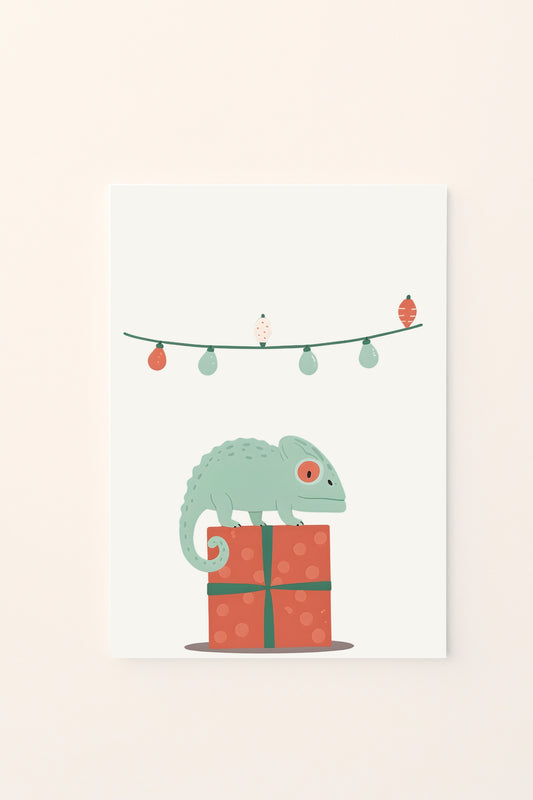 Poster decorativo per bambini con un camaleonte cartoon sopra un pacco regalo e lucine natalizie, su sfondo bianco. Simpatico e festivo.