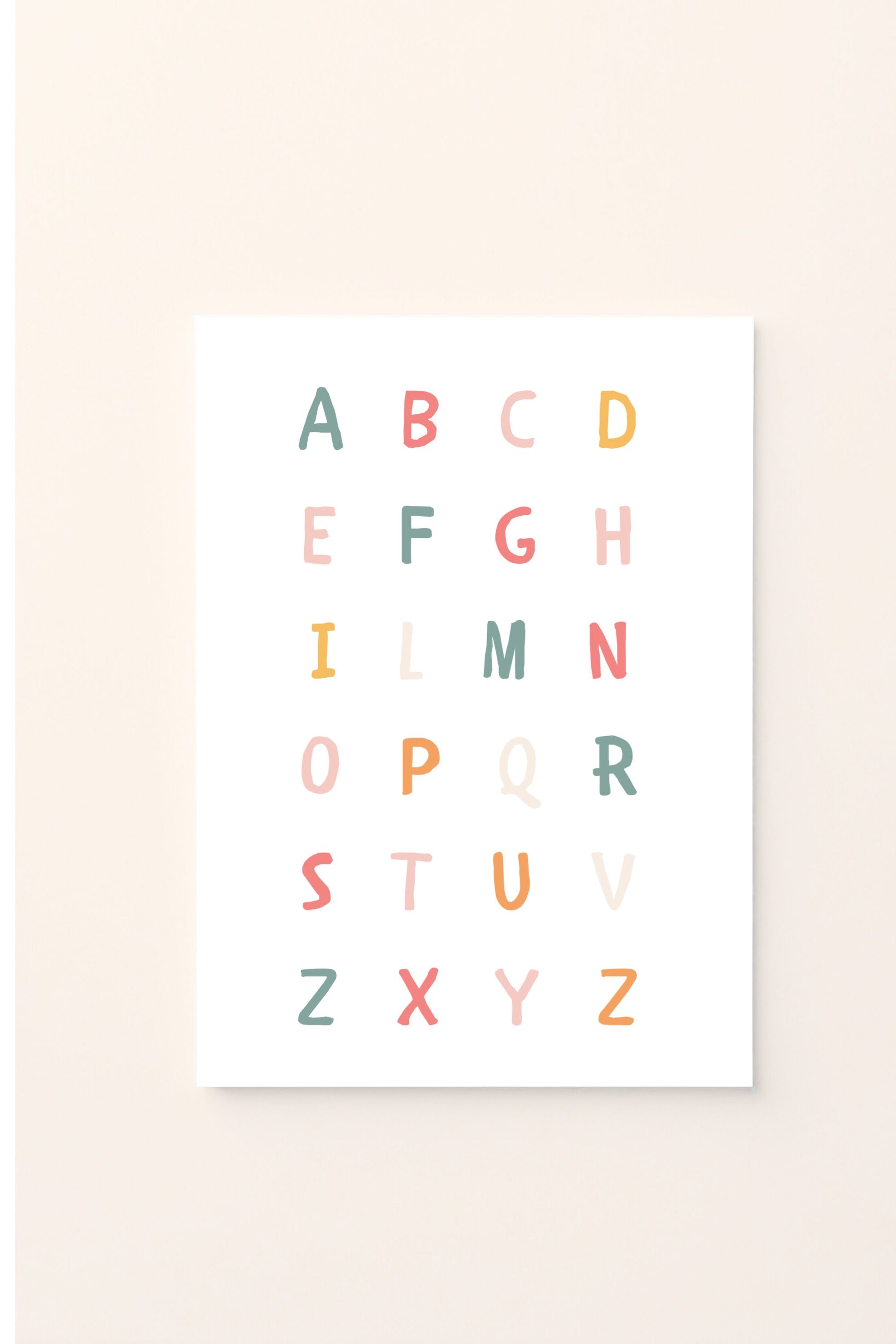 Poster educativo con alfabeto colorato in lettere maiuscole, su sfondo rosato, perfetto per decorare la cameretta e aiutare i bambini a imparare le lettere in modo giocoso e armonioso.