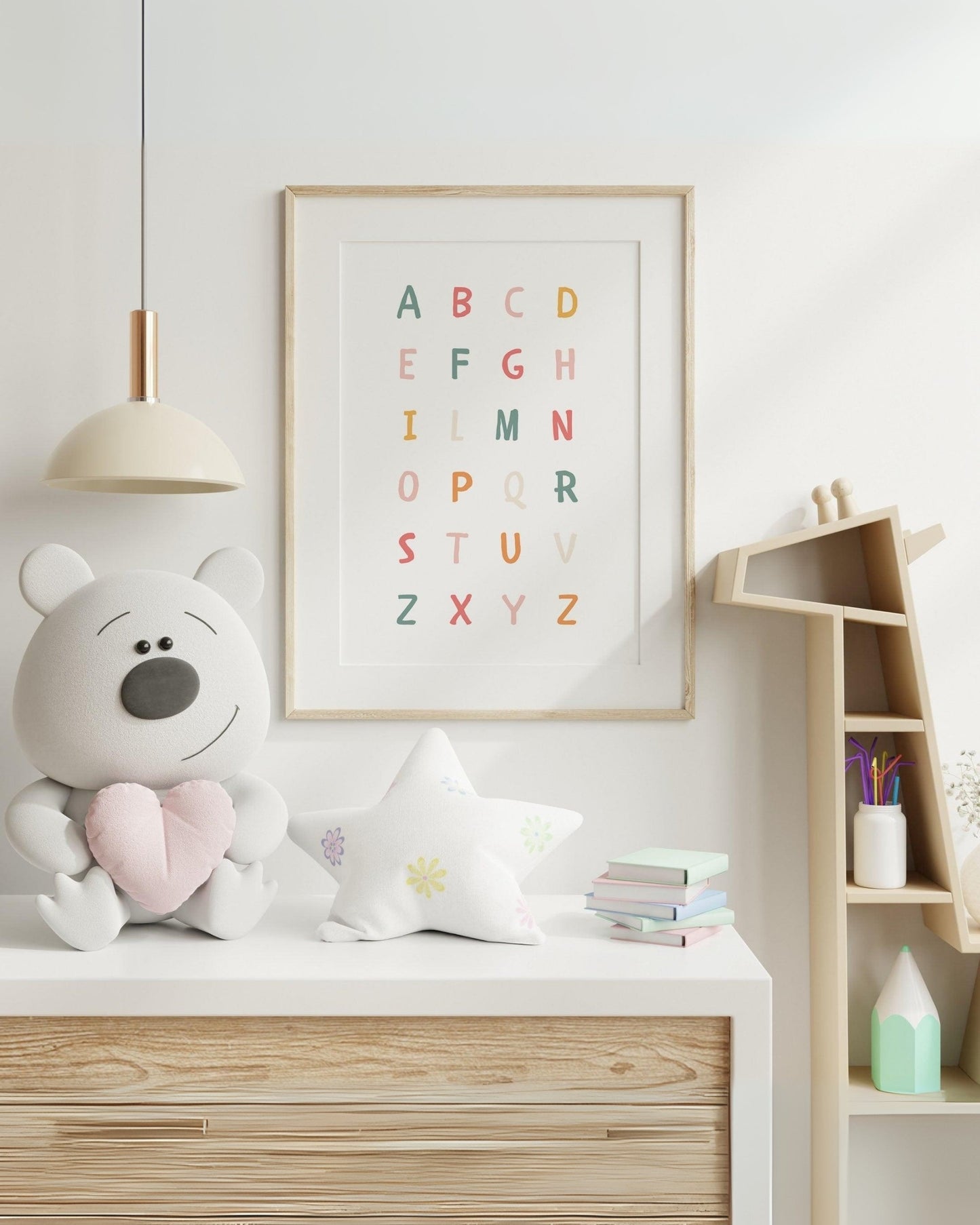 Poster con alfabeto colorato appeso al muro di una cameretta moderna, accanto a un pupazzo orsetto e decorazioni delicate.