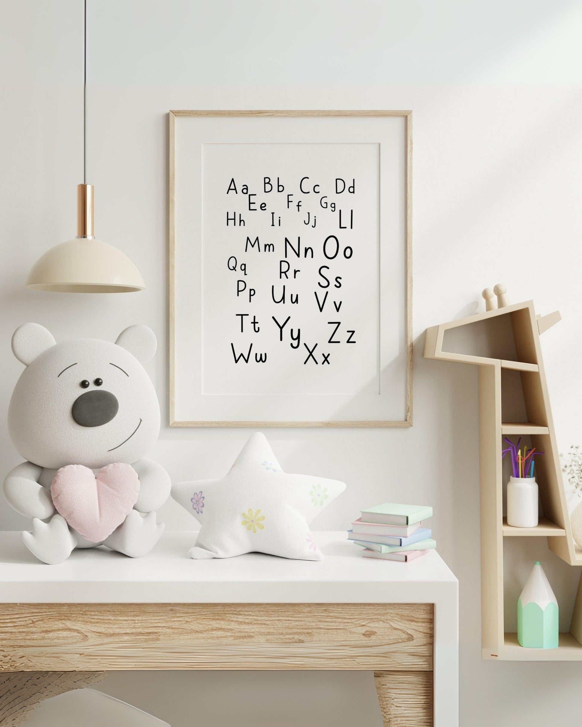 Poster alfabetico con lettere maiuscole e minuscole, appeso in cameretta moderna con peluche, stellina decorativa e mensola a casetta.