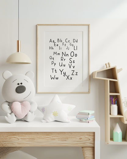 Poster alfabetico con lettere maiuscole e minuscole, appeso in cameretta moderna con peluche, stellina decorativa e mensola a casetta.