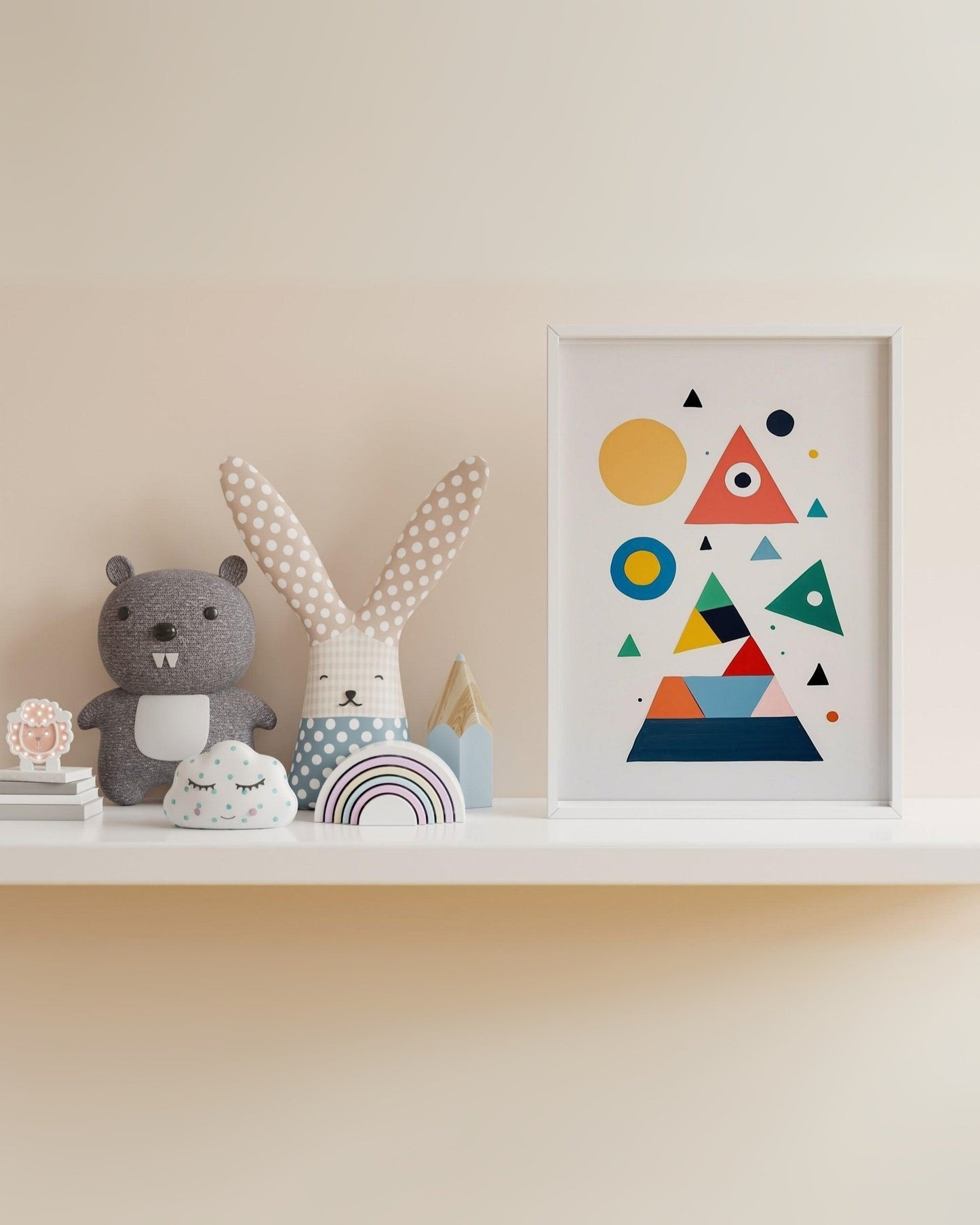 Poster per bambini con forme geometriche colorate, cornice bianca, accanto a peluche coniglio a pois.