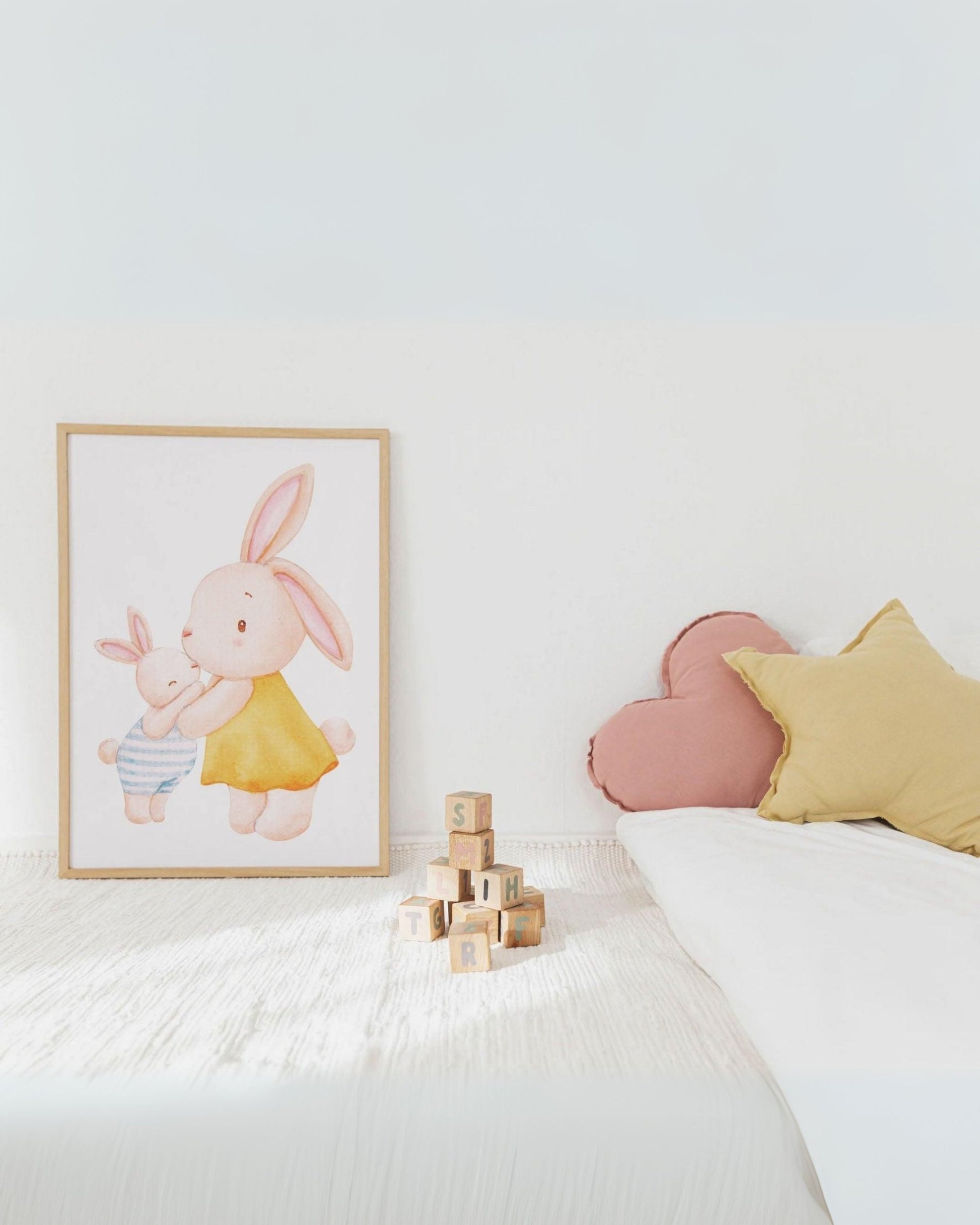 Poster con mamma coniglietta e cucciolo appoggiato su letto per bambini, con cuscini colorati e giochi in legno decorativi.