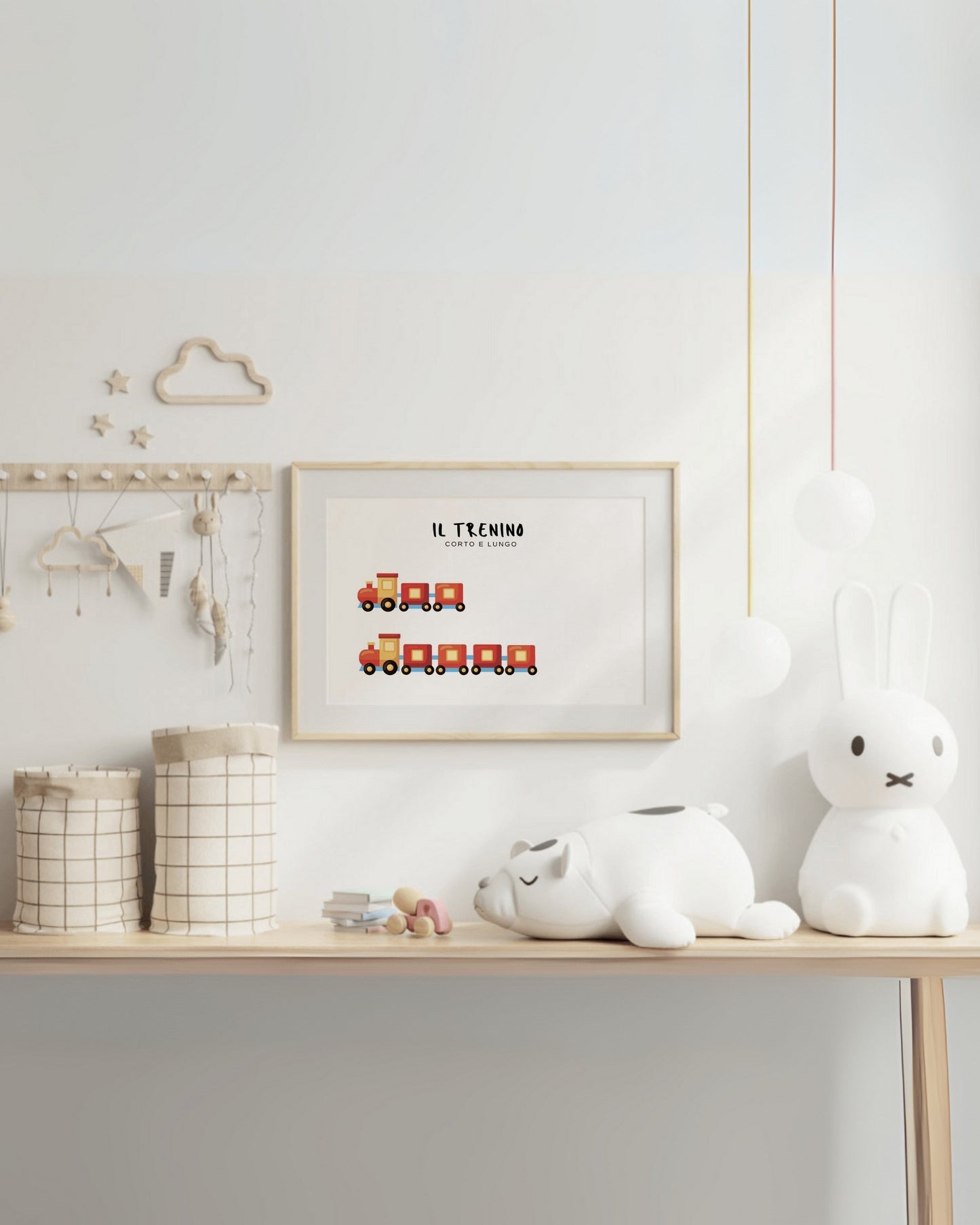 oster con trenino corto e trenino lungo in cornice chiara, appeso al muro sopra scrivania con pupazzi e oggetti decorativi.