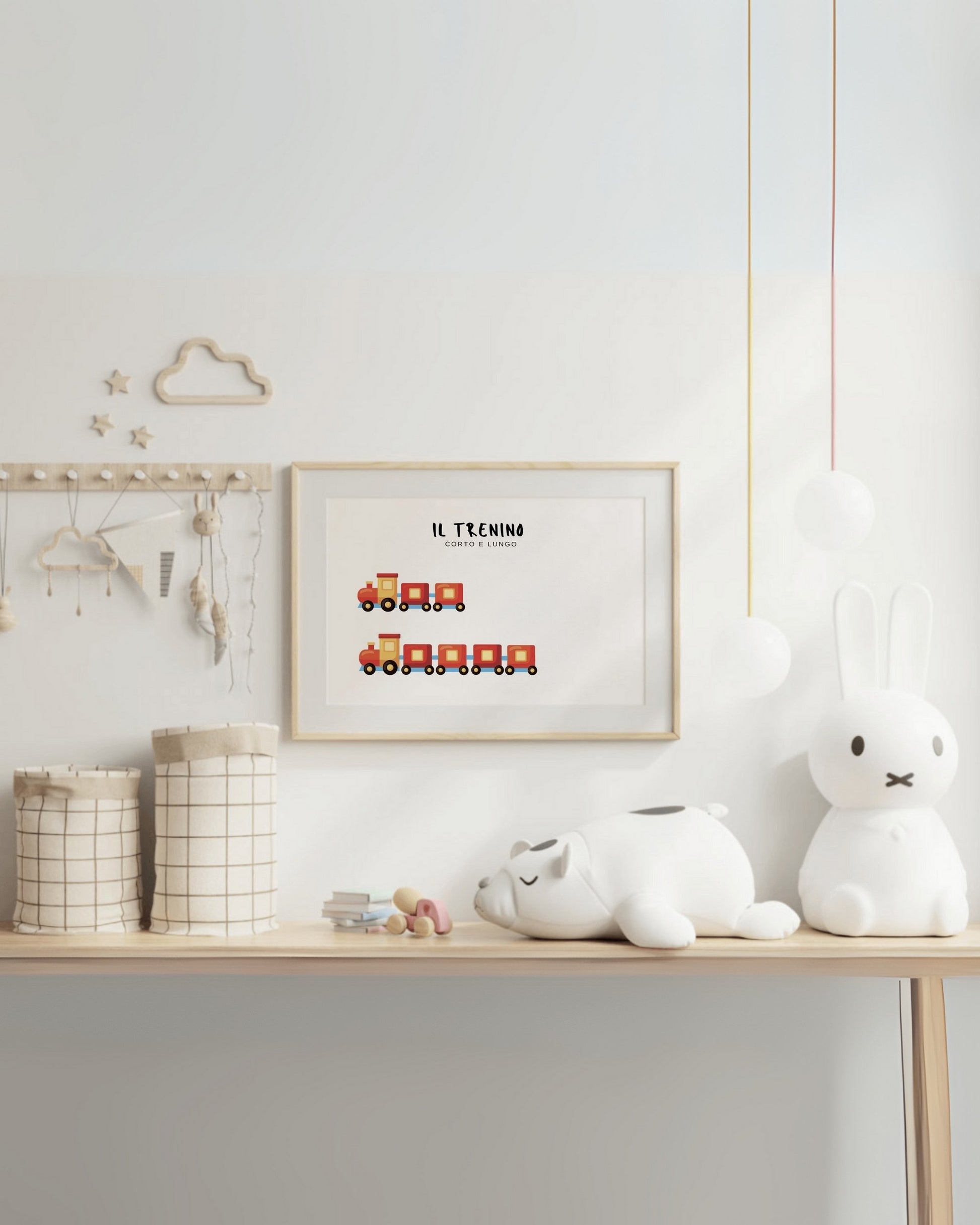 oster con trenino corto e trenino lungo in cornice chiara, appeso al muro sopra scrivania con pupazzi e oggetti decorativi.