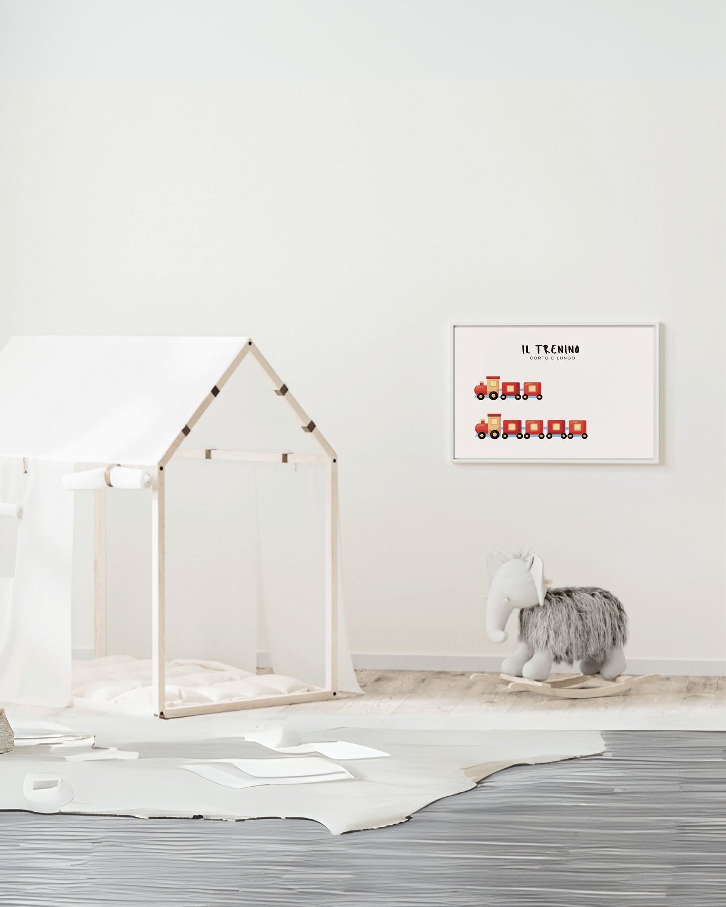 Poster con trenino corto e trenino lungo in cornice bianca, appeso al muro accanto a una casetta gioco in legno e cavalluccio morbido.