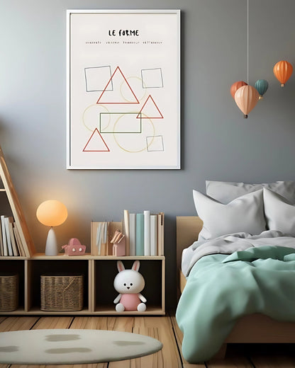 Poster con forme geometriche colorate in cornice bianca, appeso sopra un letto con coperta verde e scaffale con libri e peluche.